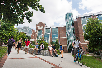 students sit and talk, walk, or ride their bikes in the sunshine