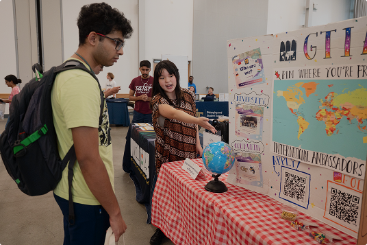 A student is shown a global studies board at a fair.
