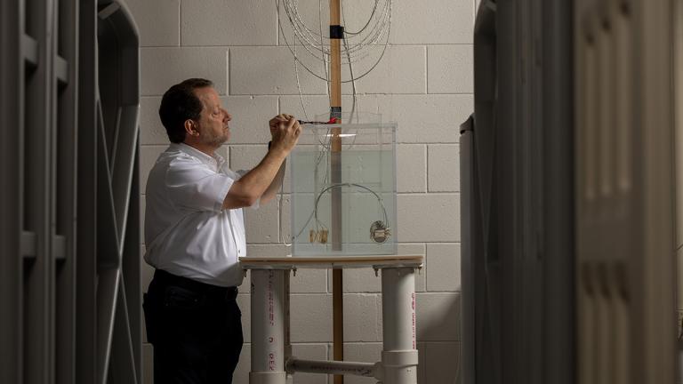 Security and logistical systems produced by various manufacturers surround a cart holding a cardiac resynchronization therapy defibrillator operating inside a torso simulator to simulate potential interactions between the device and the systems. Shown is Ralph Herkert, director of GTRI’s Medical Device Test Center. 